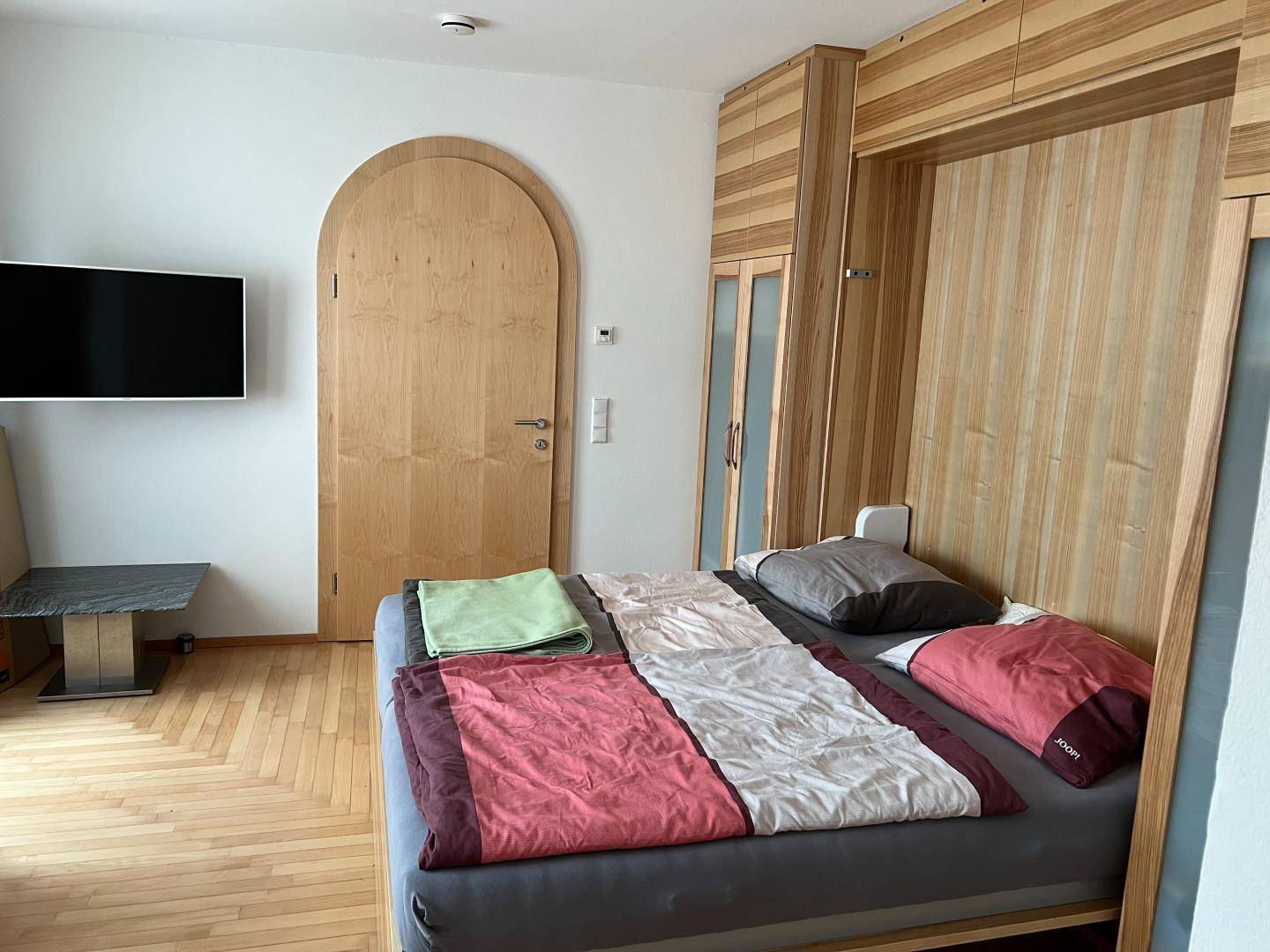 Schlafzimmer mit Holzboden, integriertem Bett und Holzelementen an der Wand.