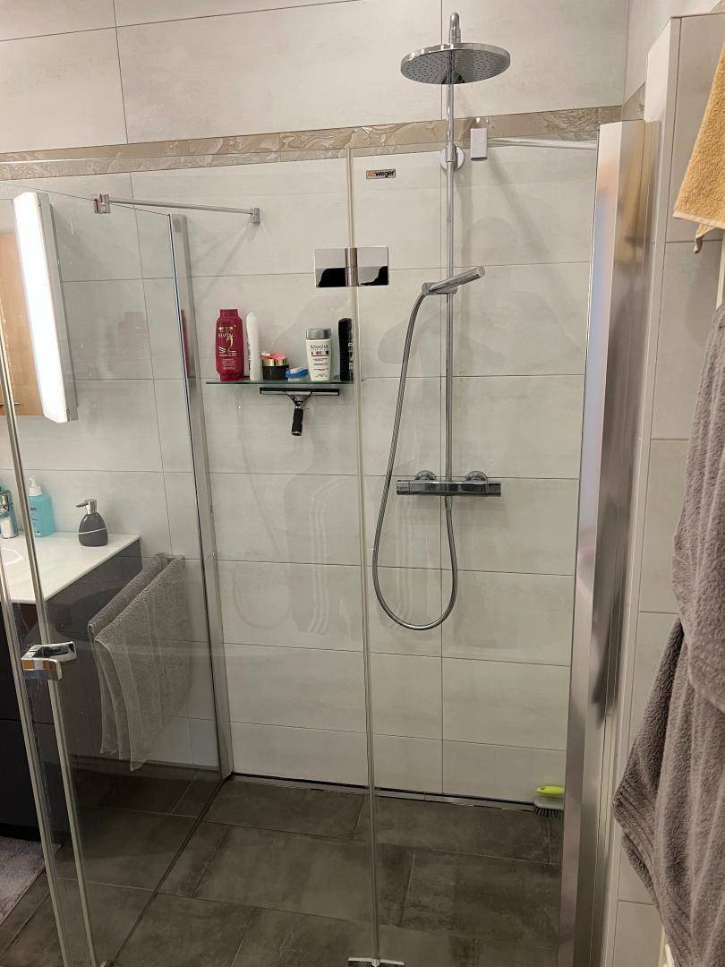 Moderne Duschkabine mit Regendusche und großformatigen Fliesen an der Wand.