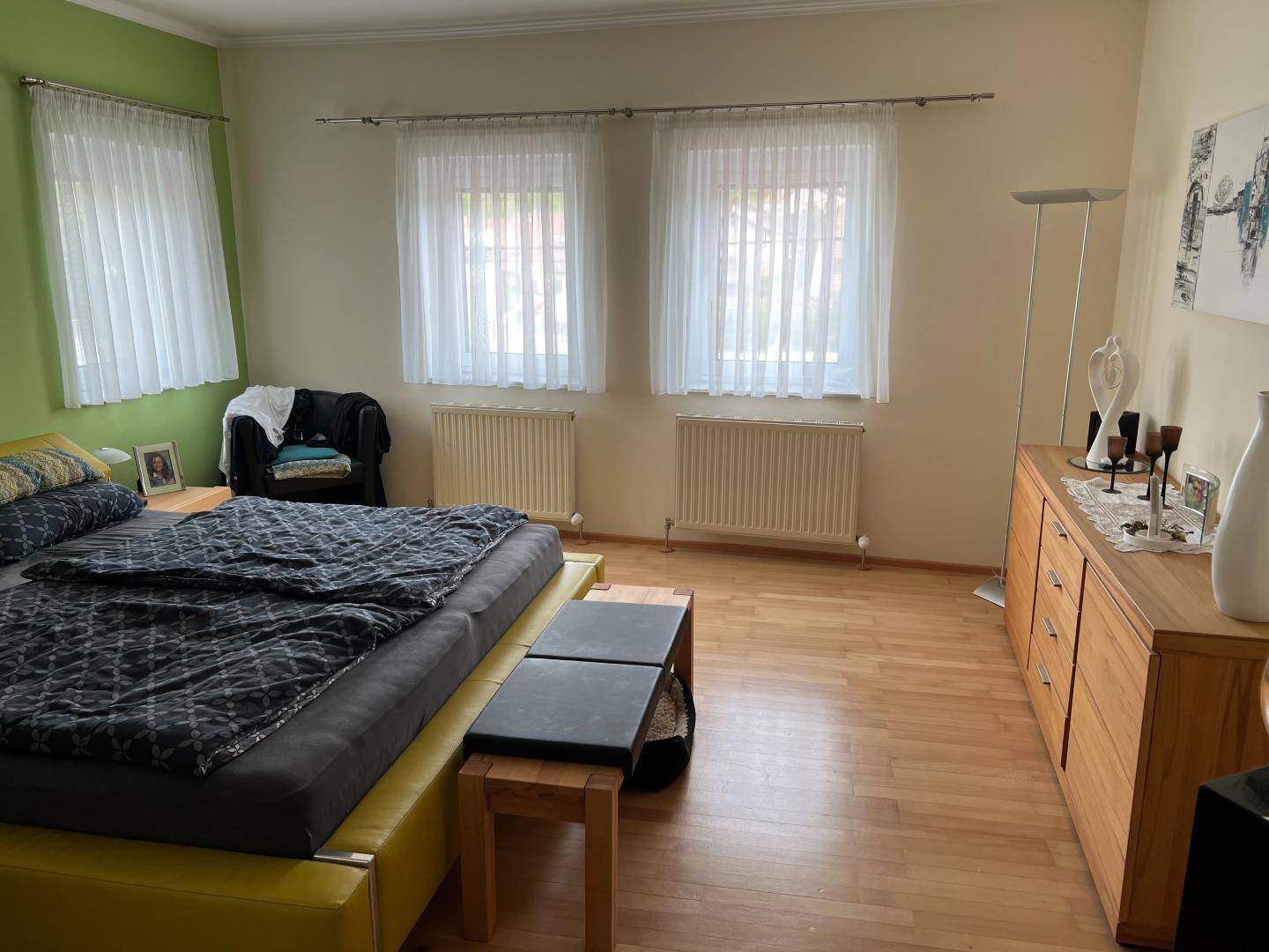 Schlafzimmer mit Holzboden, Doppelbett und grüner Akzentwand.