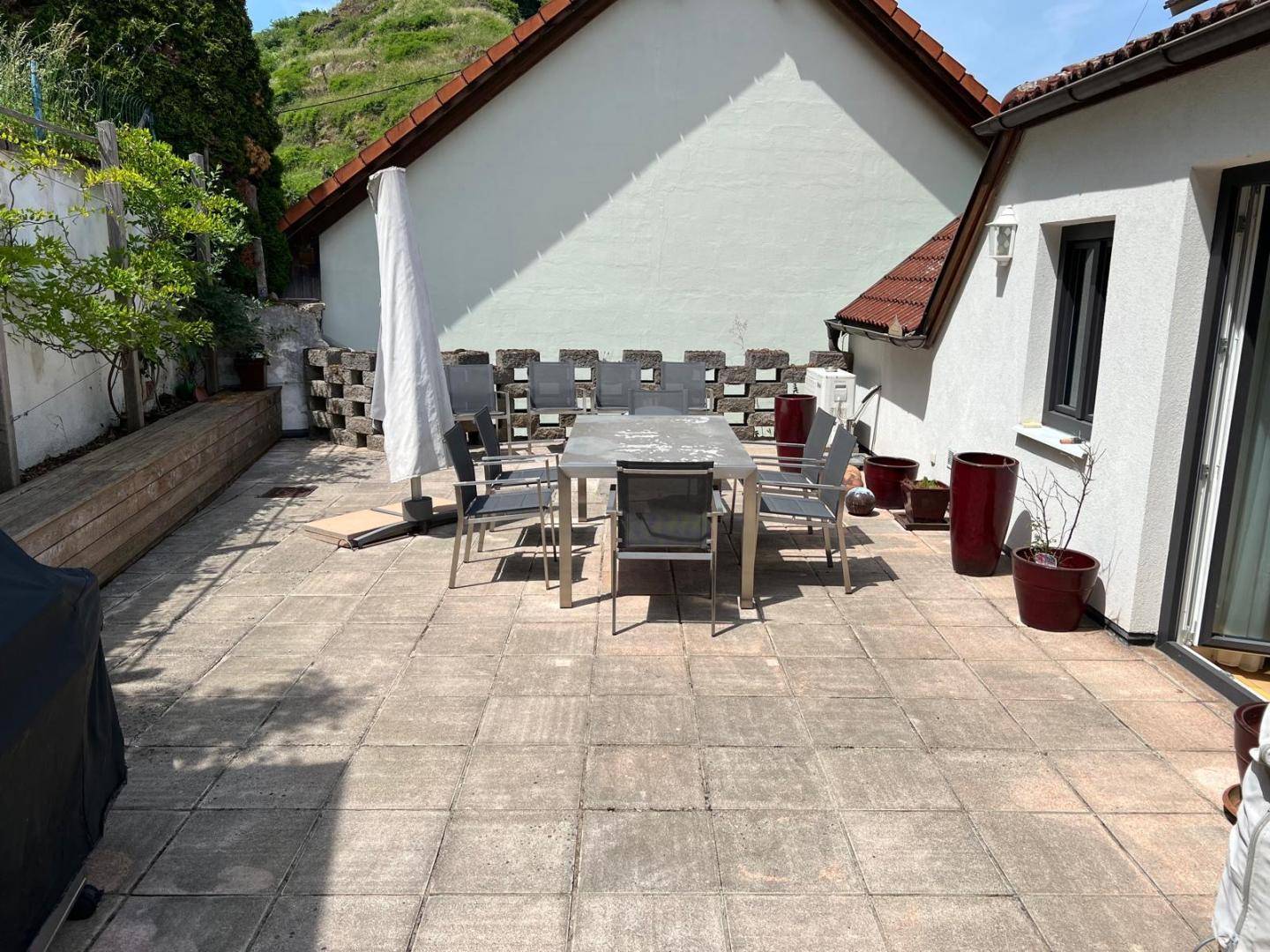 Geräumige gepflasterte Terrasse mit Gartenmöbeln und weitem Blick auf die grüne Umgebung.