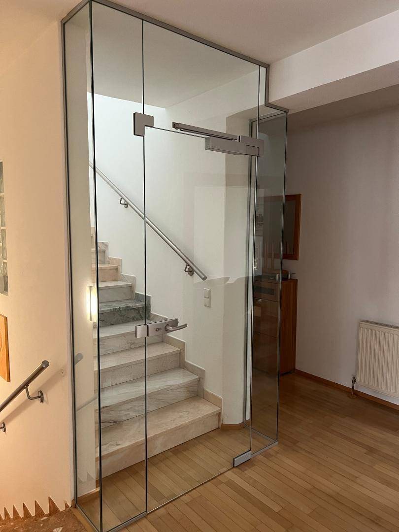 Elegantes Treppenhaus mit Glasabtrennung, Marmorstufen und Edelstahlgeländer.