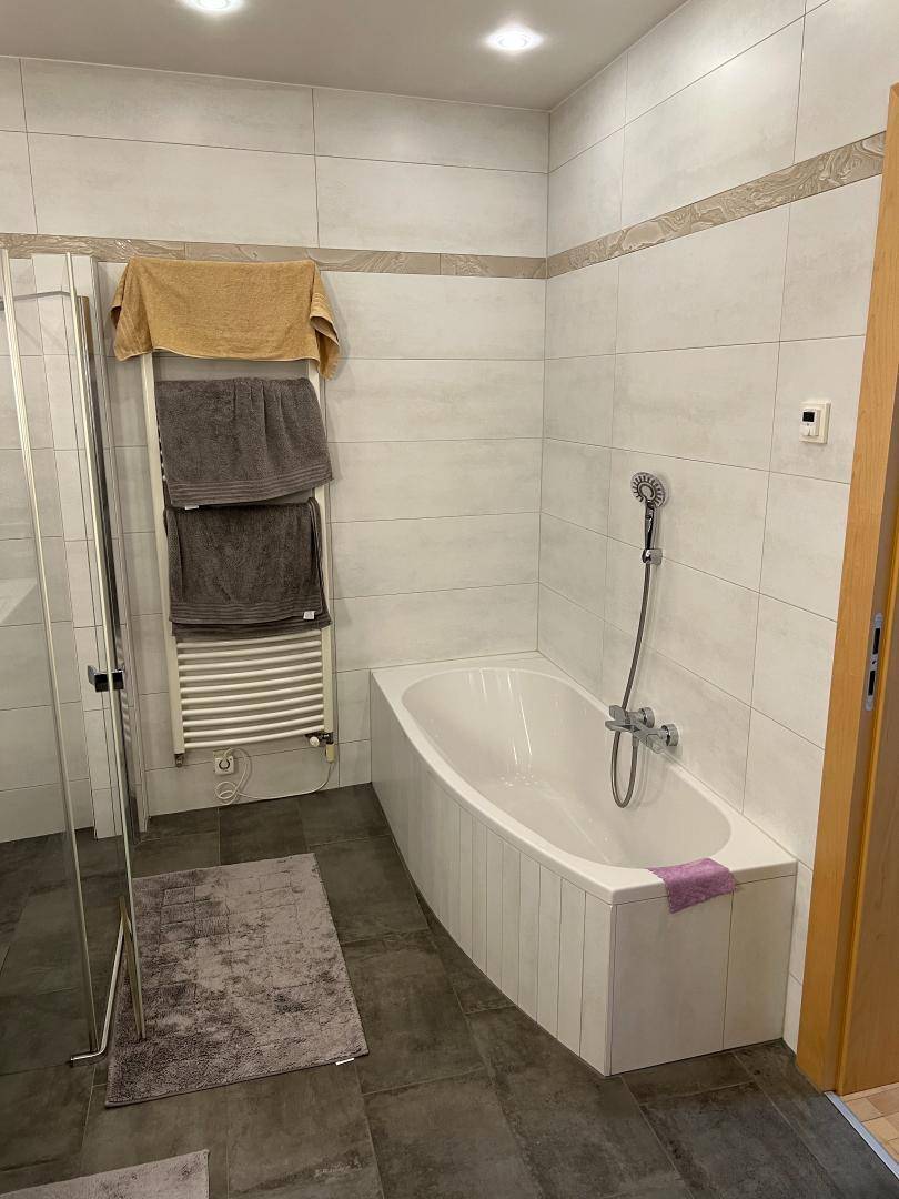 Modernes Badezimmer mit Badewanne, Duschkabine und beheiztem Handtuchhalter.