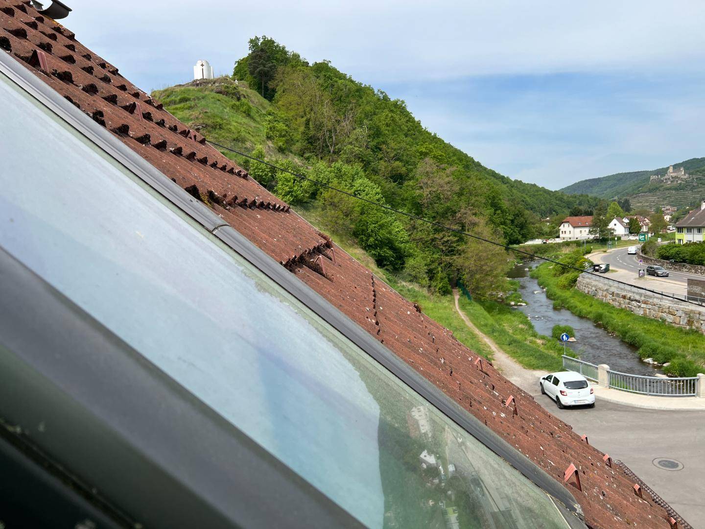 Panoramablick über die Dächer, grüne Hügel, einen Fluss und die umliegende Landschaft.