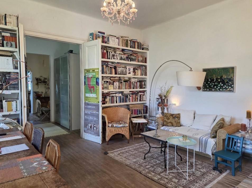 Wohnbereich mit Bücherregalen, Sofa und Esstisch, verbunden durch eine offene Tür.