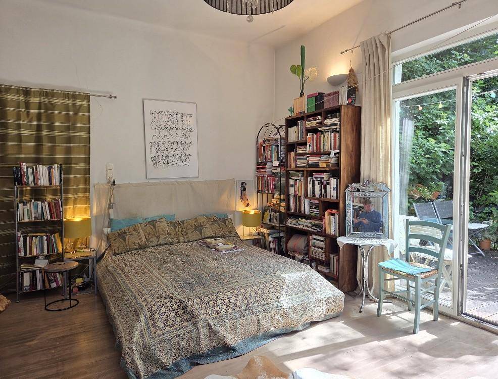 Gemütliches Schlafzimmer mit großem Bett, Bücherregalen und direktem Zugang zur Terrasse.
