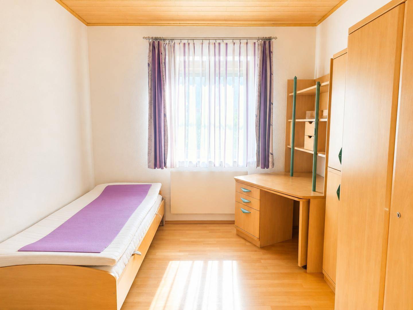 Helles Kinderzimmer mit Einzelbett, Schreibtisch und Kleiderschrank, ideal für junge Bewohner.