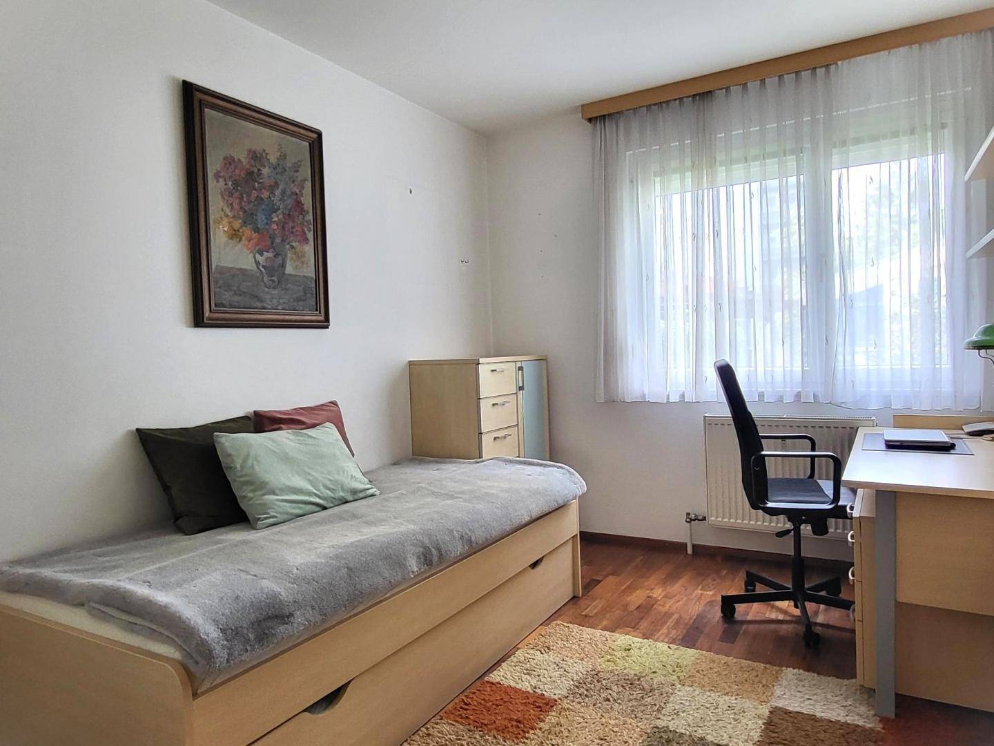 Helles Kinder- oder Gästezimmer mit Einzelbett, Schreibtisch und Blick ins Grüne.