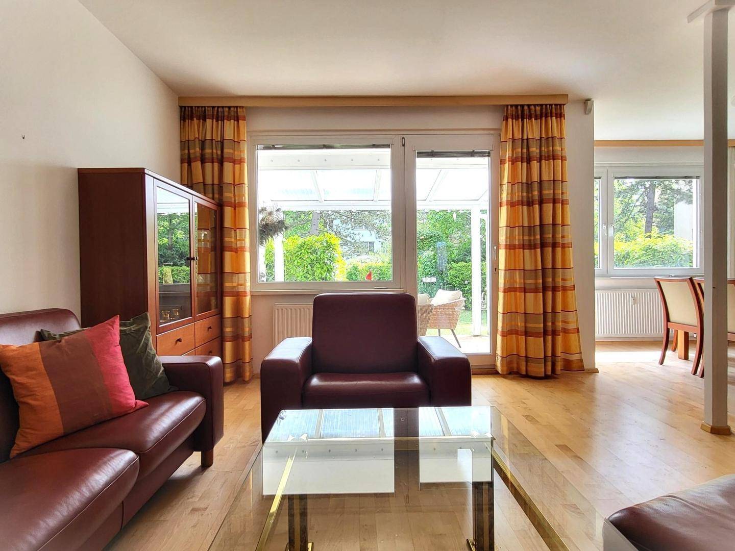 Gemütliches Wohnzimmer mit Ledersofa, Couchtisch und Blick in den Garten.