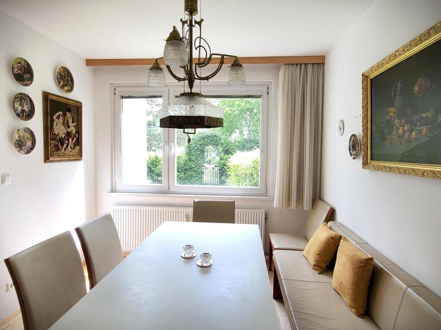 Heller Essbereich mit großem Fenster, Holzboden und traditioneller Deckenleuchte.