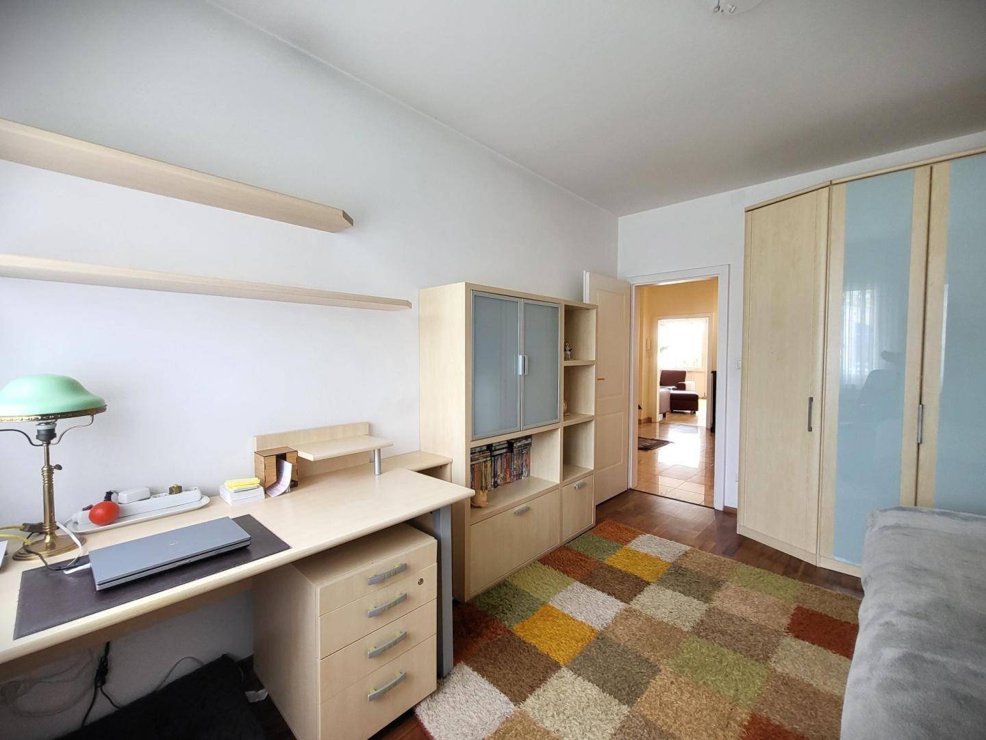 Funktionales Zimmer mit Schreibtisch, Regal und Schrank, ideal als Büro oder Gästezimmer.
