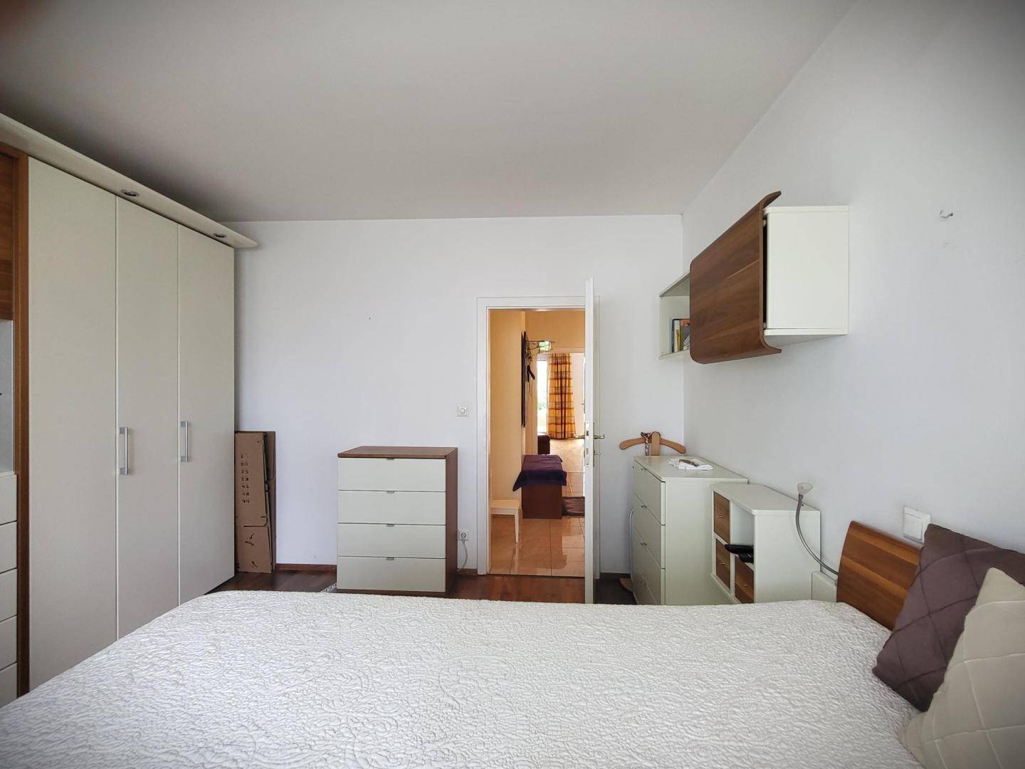 Schlafzimmer mit großem Bett, weißem Kleiderschrank und Holzboden.