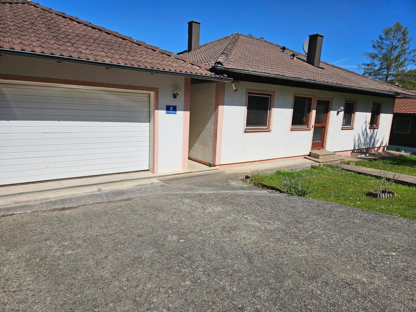 Vorderansicht des Hauses mit integrierter Garage und einer gepflasterten Zufahrt.
