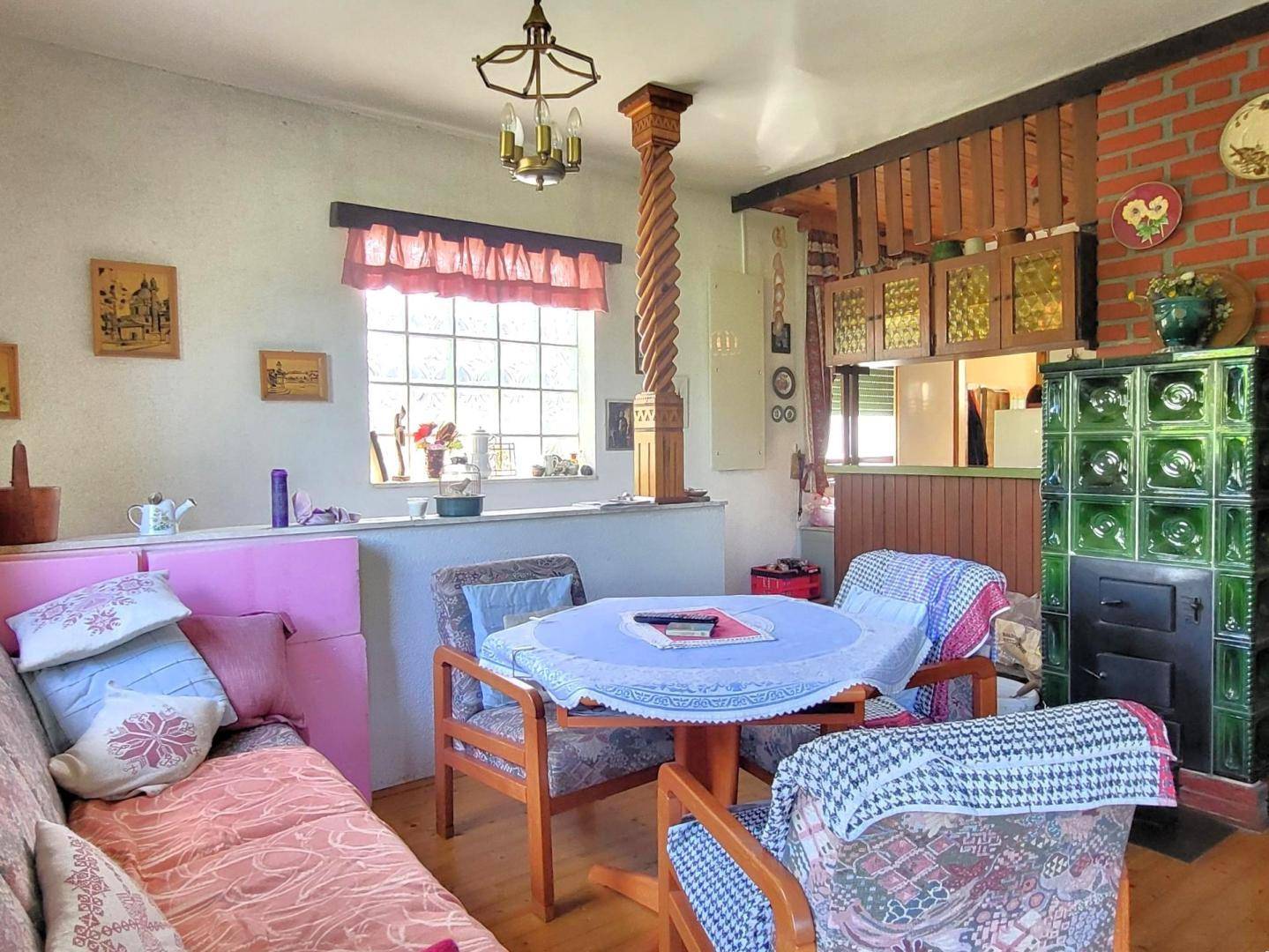 Wohnzimmer mit traditionellem Kachelofen, Holzbalken und gemütlicher Sitzecke.