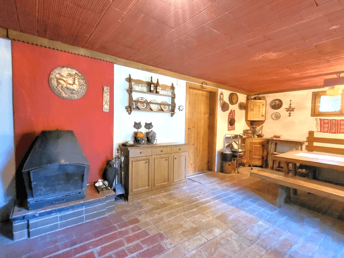 Gemütlicher Kellerraum mit Holzbänken, Kamin und traditionellen Wanddekorationen.