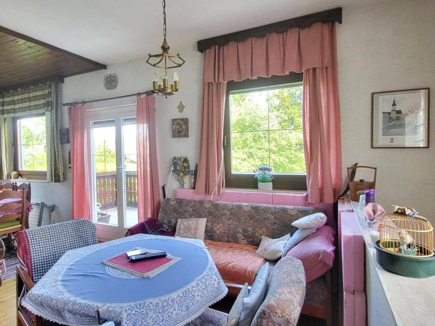 Helles Wohnzimmer mit Balkonzugang, gemütlicher Couch und Blick in die Natur.