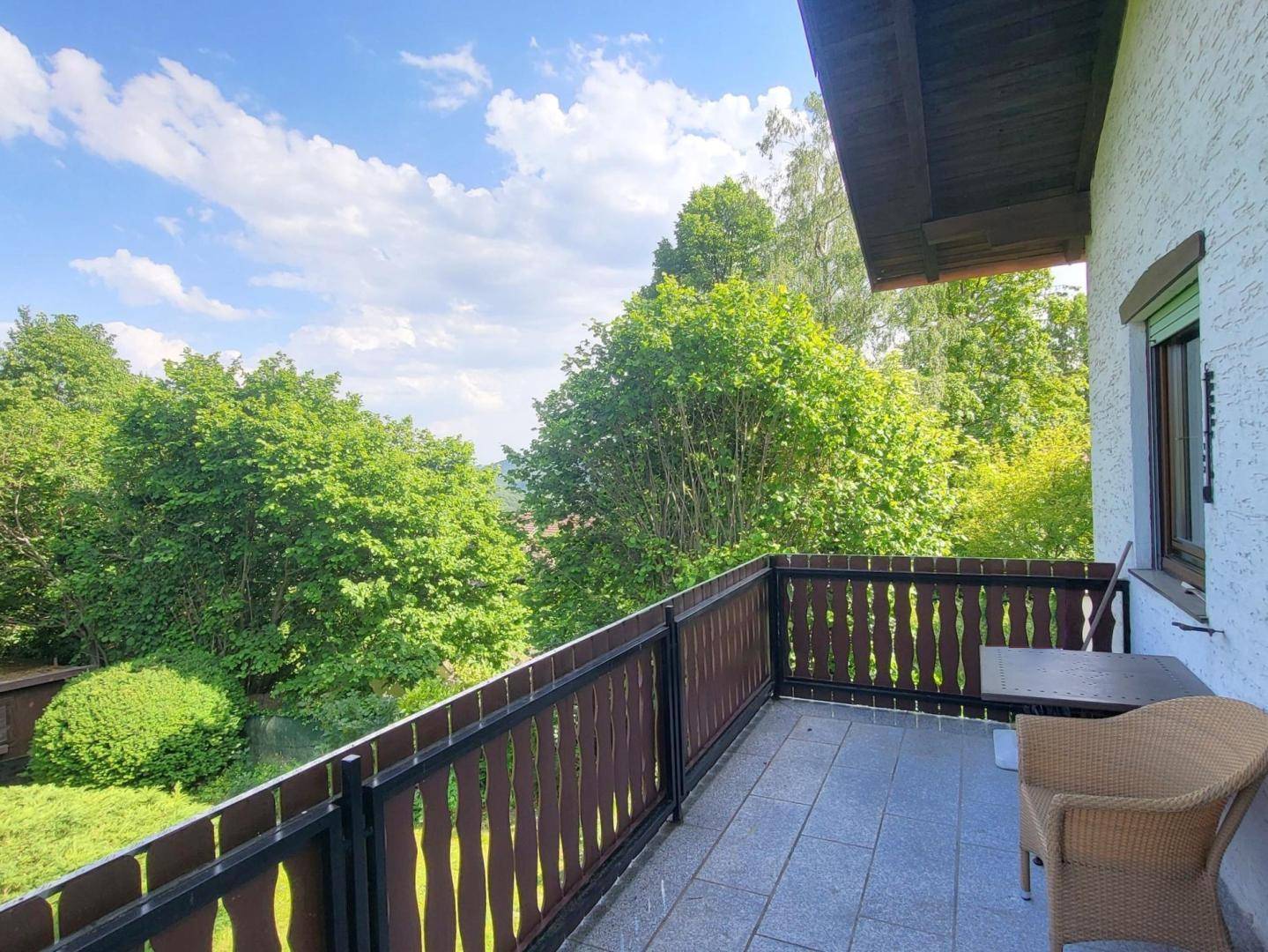 Geräumiger Balkon mit Holzbalkonbrüstung und weitem Blick über die grüne Landschaft.