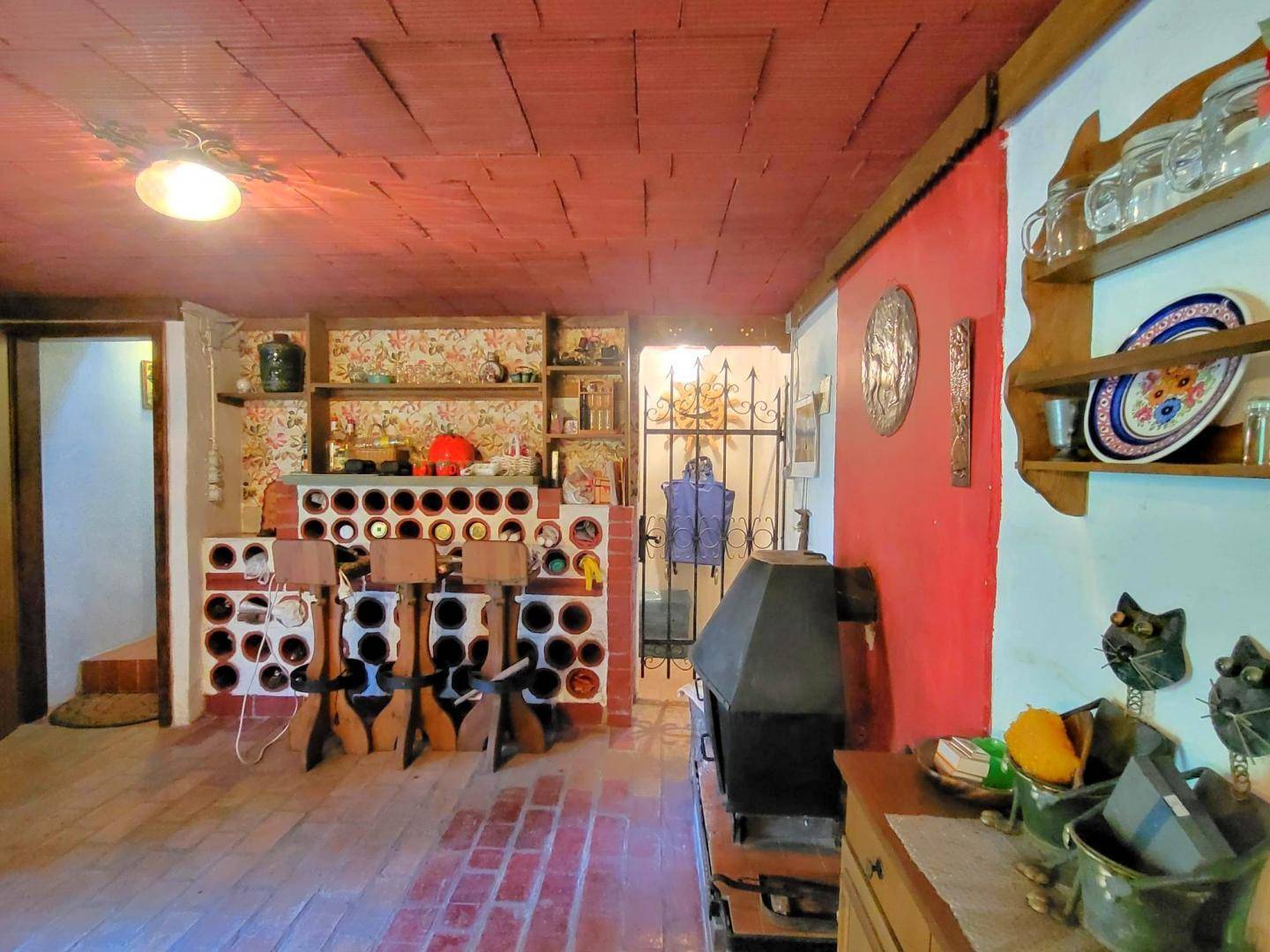 Rustikaler Kellerraum mit Ziegelboden, Weinregalen und einem Holzofen.