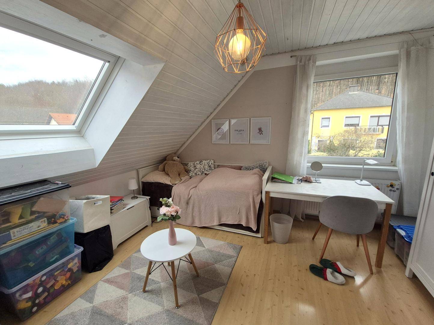 Helles Schlafzimmer im Dachgeschoss mit Dachschräge, Dachfenster und einem Einzelbett.