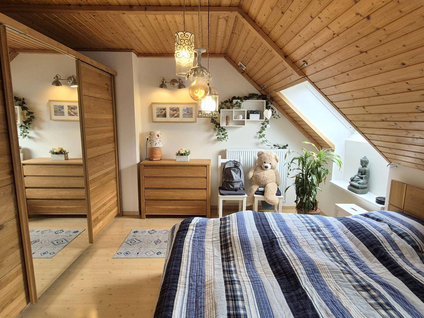 Schlafzimmer im Dachgeschoss mit Holzverkleidung an Decke und Wänden, sowie einem Dachfenster.