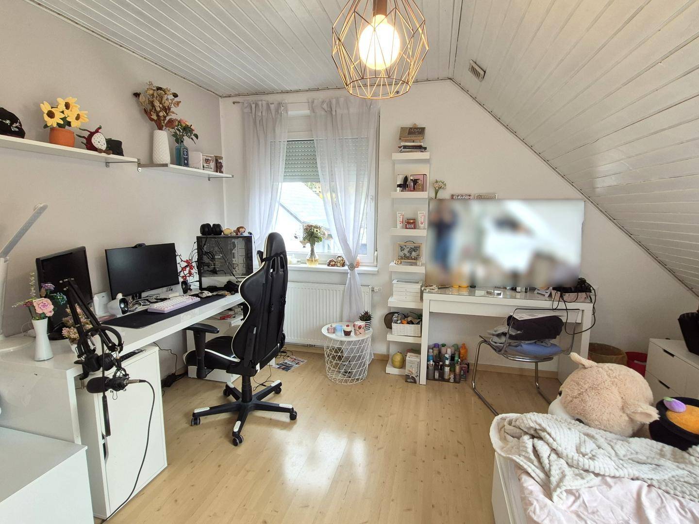 Modernes Arbeitszimmer im Dachgeschoss mit Schreibtisch, Gaming-Setup und Dachschräge.