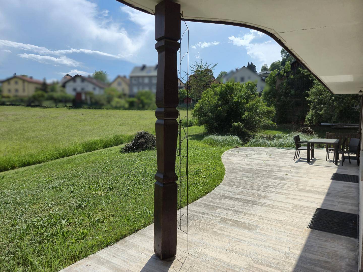 Terrasse mit Blick auf weite grüne Felder und die umliegende Wohnbebauung.