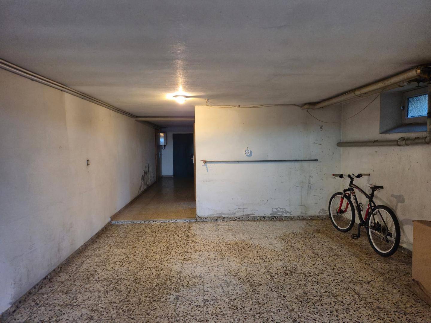 Geräumiger Kellerraum mit Fahrrädern und Terrazzoboden, nutzbar als Abstell- oder Hobbyraum.