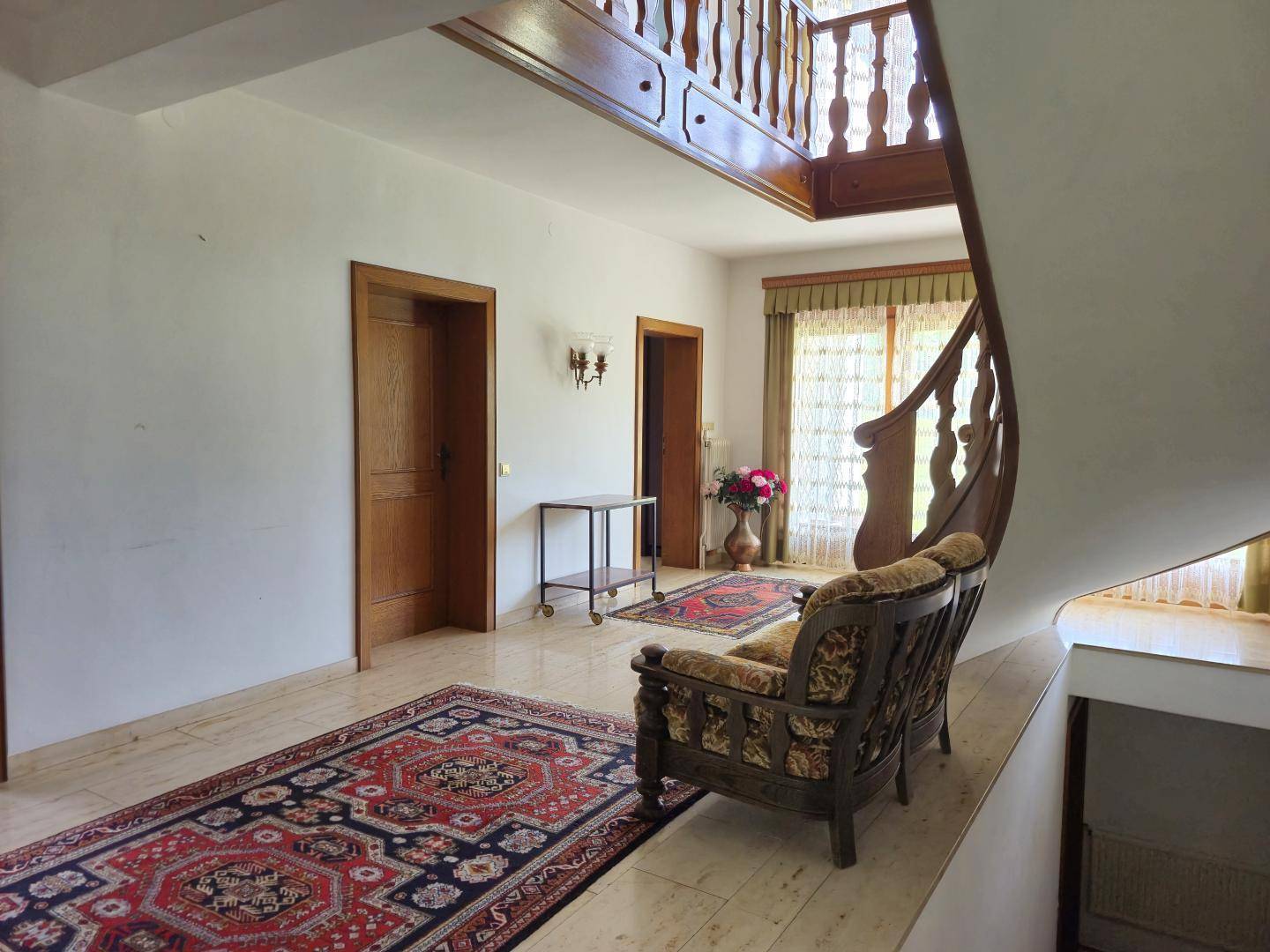 Geräumiger Eingangsbereich mit traditioneller Holztreppe und gemusterten Teppichen.
