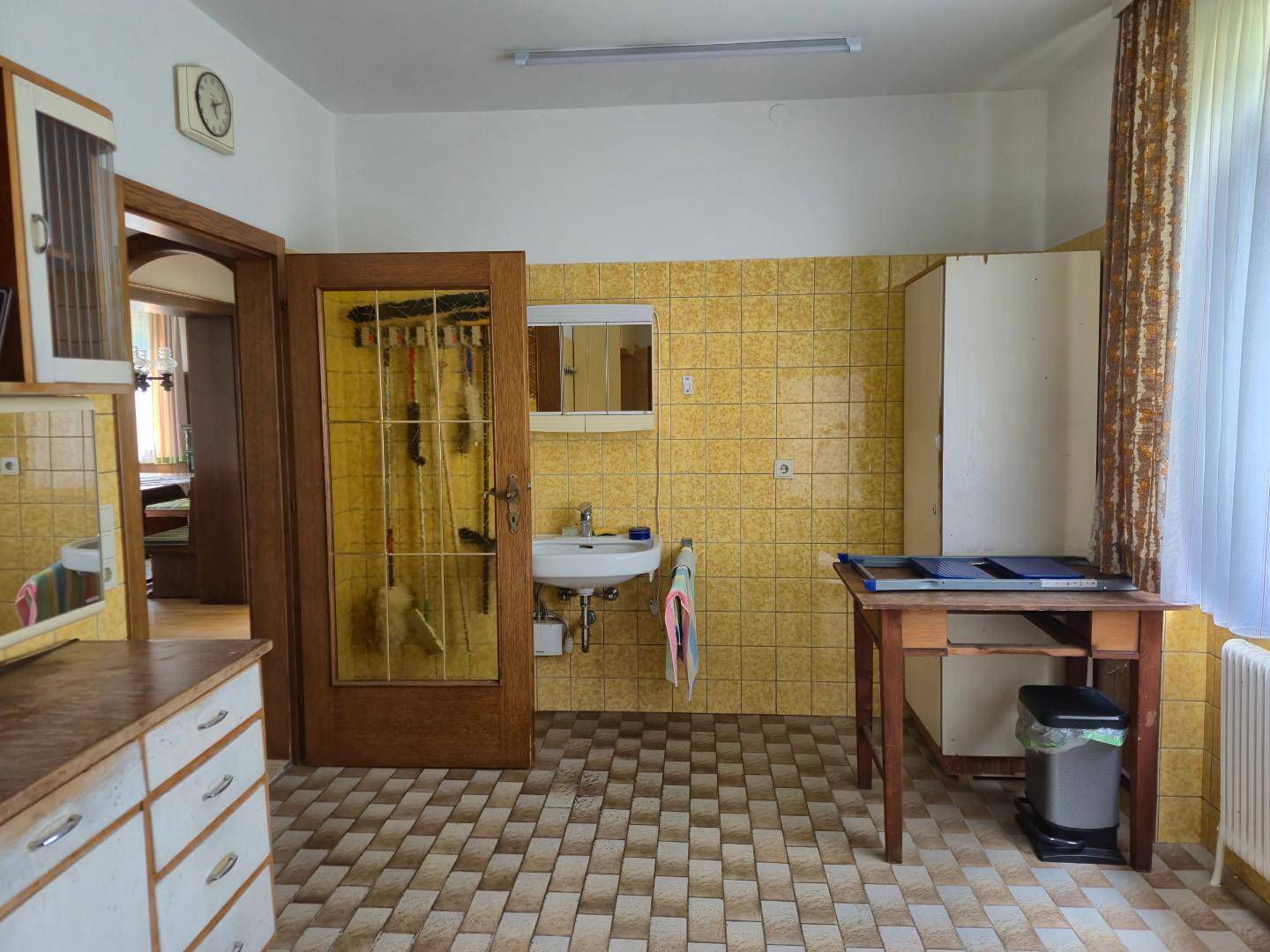 Hauswirtschaftsraum oder Nebenküche mit gelben Fliesen, Spülbecken und Fenster.