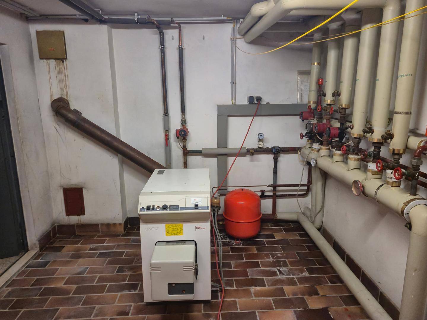Heizungsraum im Keller mit Pelletkessel und umfangreicher Rohrinstallation.