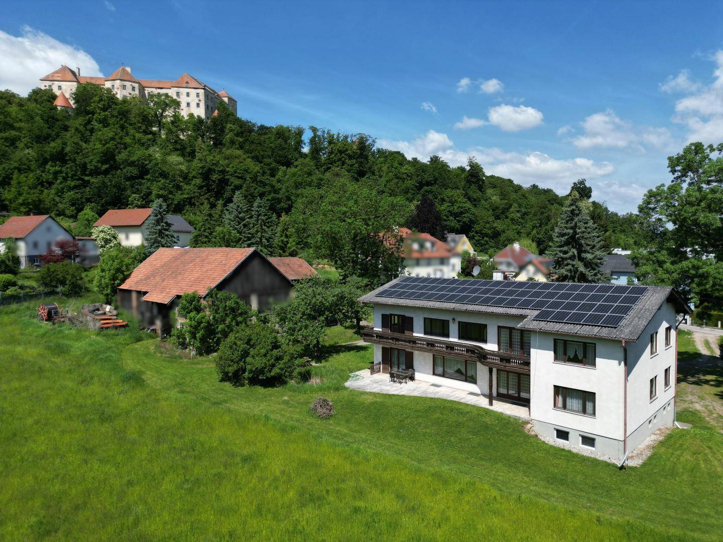 Luftaufnahme des Hauses mit Photovoltaikanlage und Blick auf eine historische Burg.