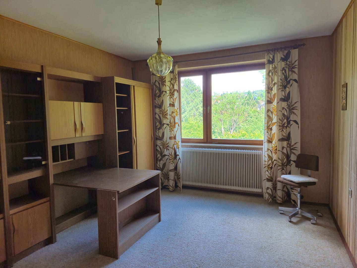Schlafzimmer oder Büro mit Teppichboden, Holzmöbeln und Blick auf die Landschaft.
