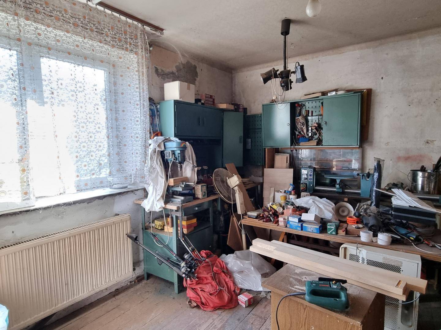 Werkstattraum mit Werkbänken, Schränken und großem Fenster.