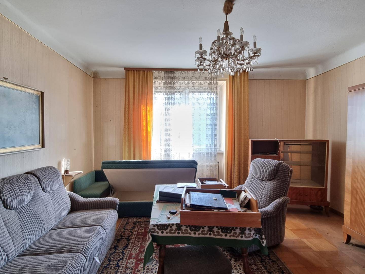 Wohnzimmer im Vintage-Stil mit Kronleuchter, gemusterten Tapeten und Parkettboden.