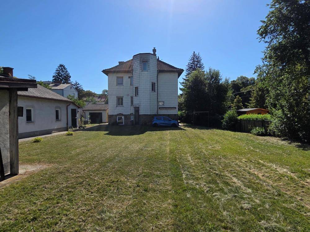 Weitläufiger Gartenbereich hinter dem Haus mit Rasenfläche und Bäumen.