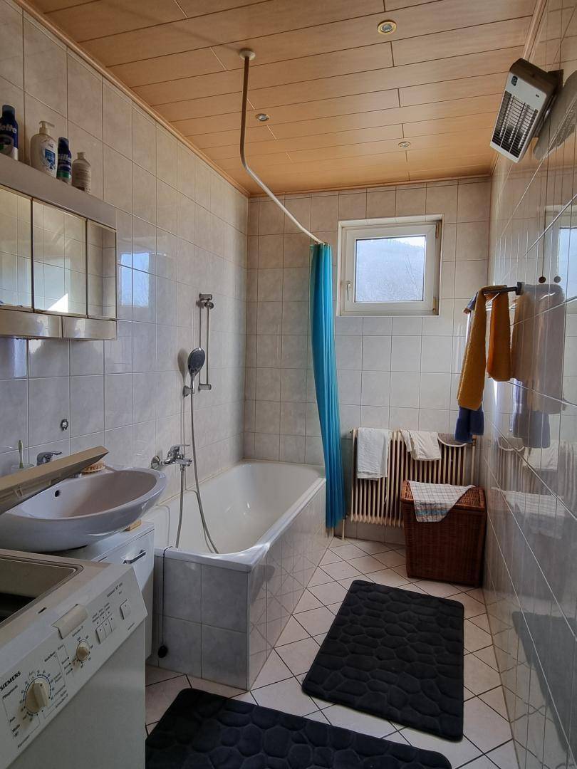 Badezimmer mit Badewanne, Waschbecken, Fliesen und Fenster.