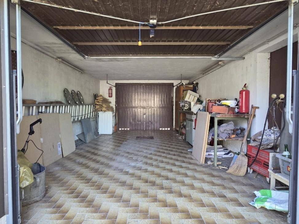 Geräumige Garage mit Fliesenboden, Lagerflächen und Doppeltor.