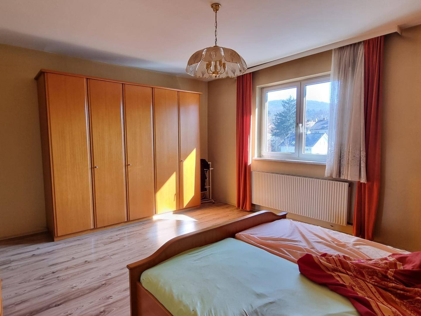Schlafzimmer mit großem Kleiderschrank, Laminatboden und Fenster mit Ausblick.