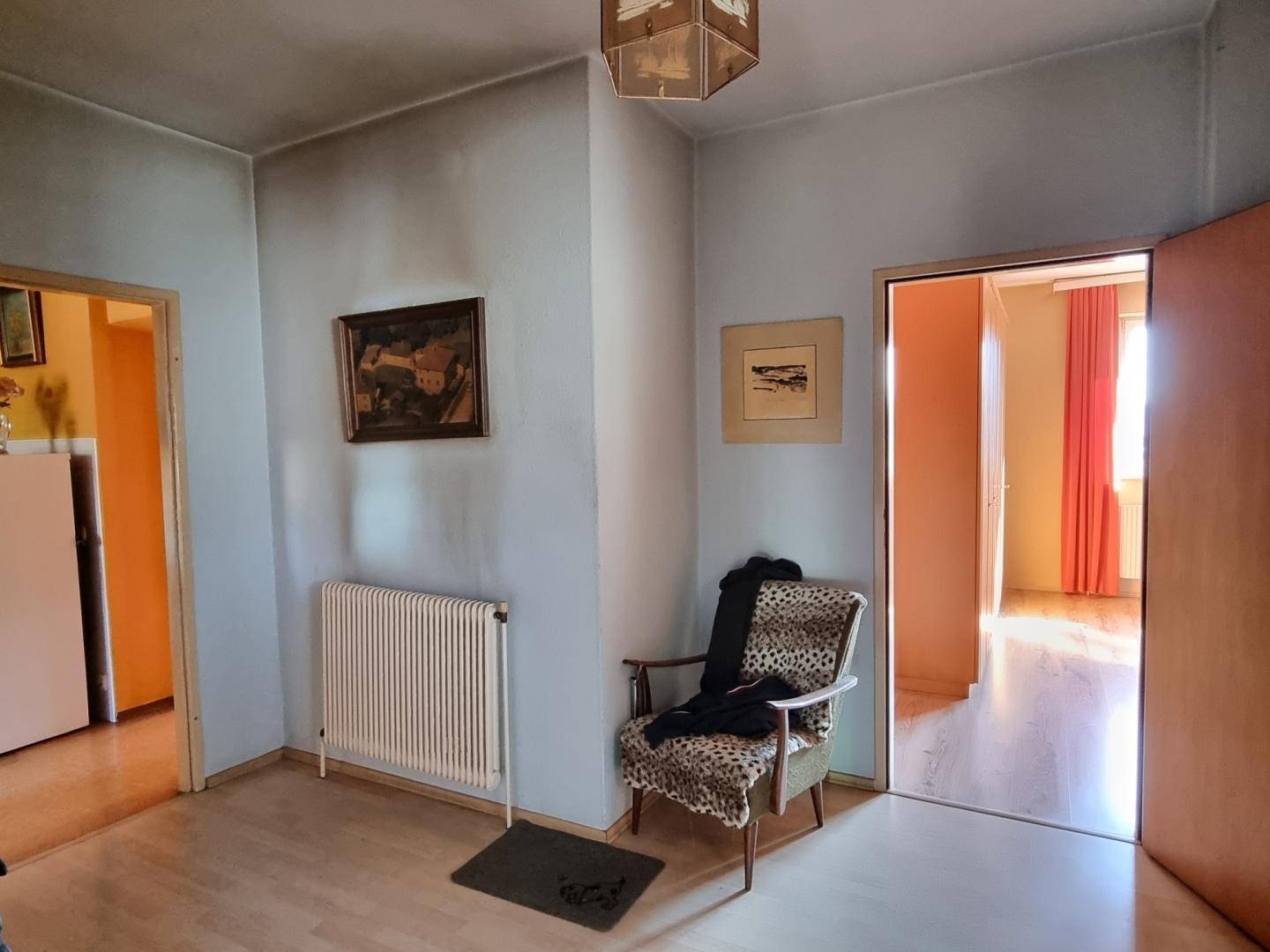 Heller Flur mit Laminatboden, Heizkörper und Zugang zu angrenzenden Räumen.