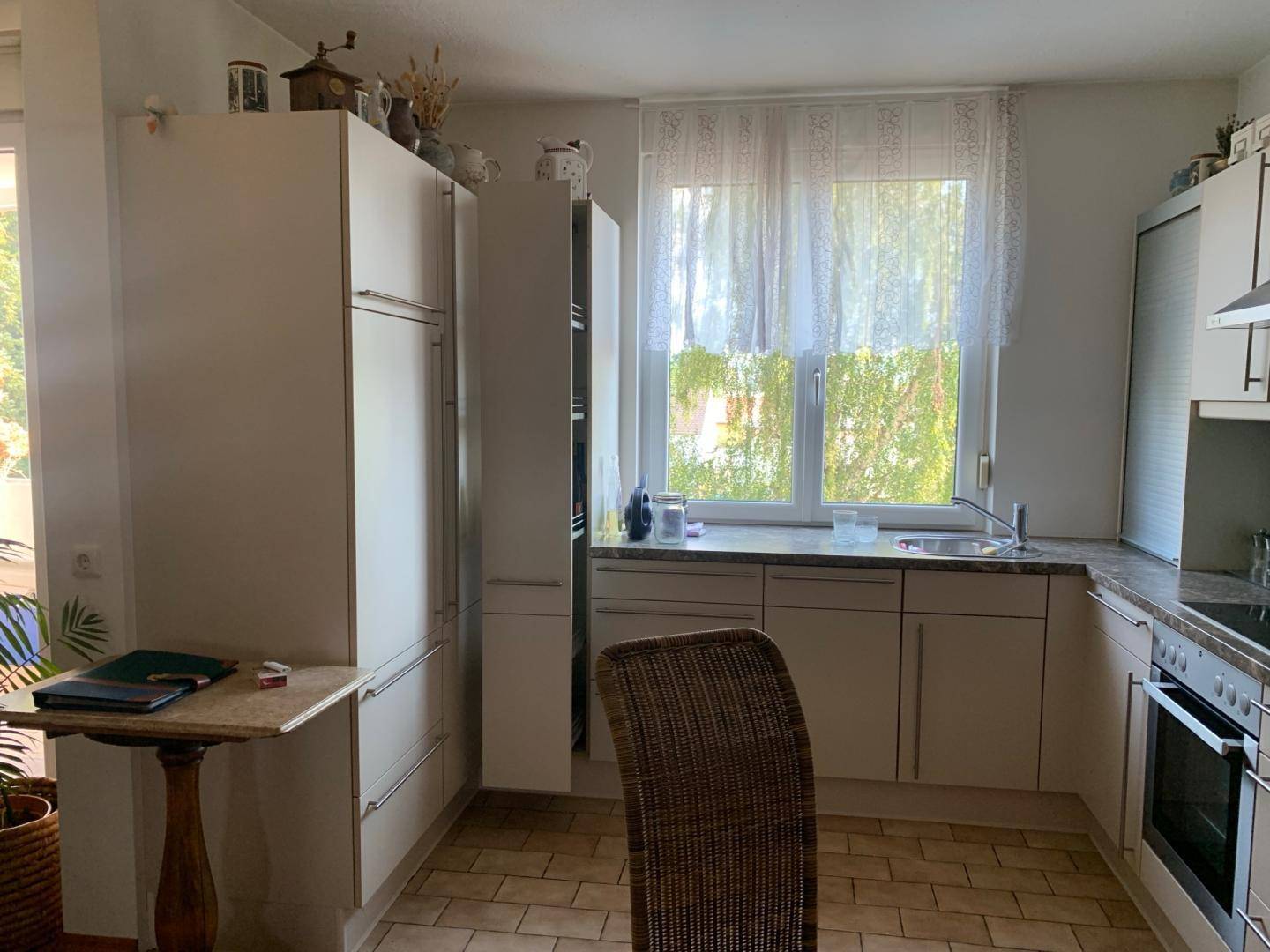 Küchenzeile mit integriertem Kühlschrank, Spüle und Arbeitsplatte, gut beleuchtet durch ein großes Fenster.