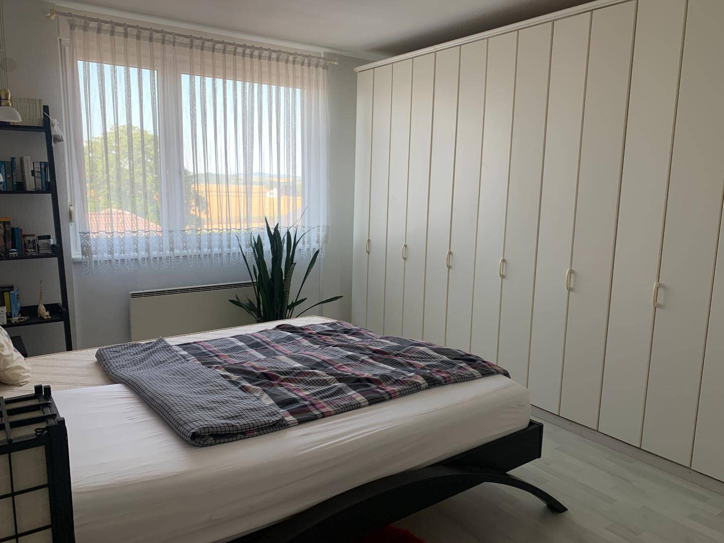Schlafzimmer mit großem Bett, Einbauschränken und Fenster mit Blick auf die Umgebung.