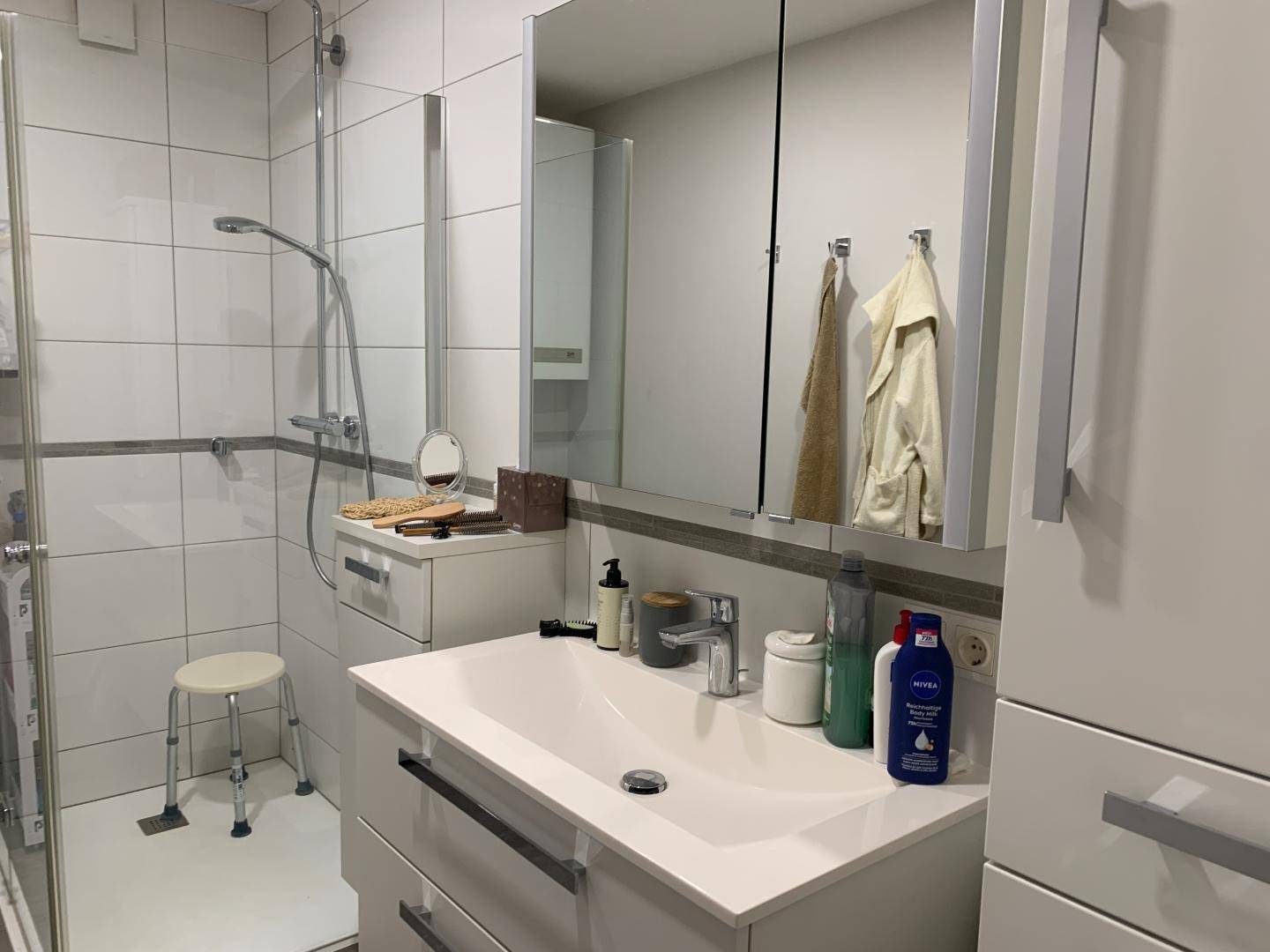 Modernes Badezimmer mit Duschkabine, Einzelwaschbecken und Spiegelschrank.