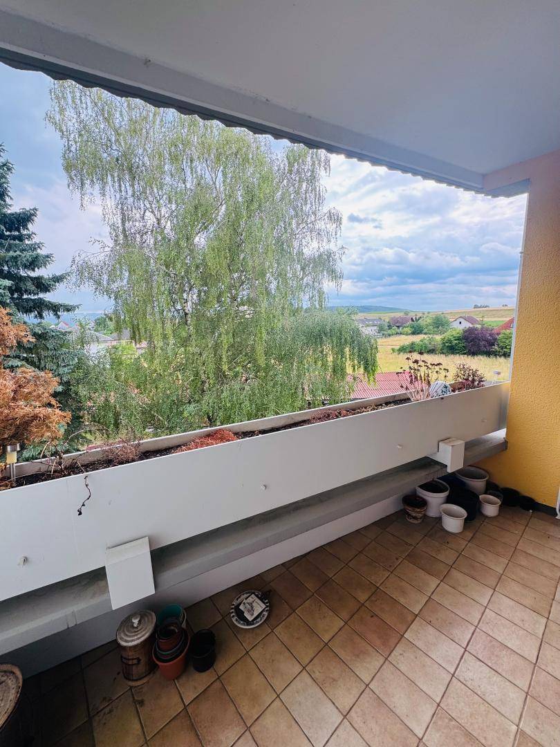 Balkon mit Fliesenboden und weitem Blick über die grüne Landschaft.