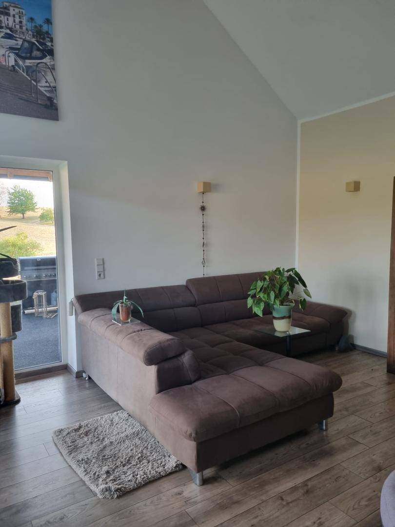 Gemütliche Sofaecke im Wohnzimmer mit hohen Decken und Zugang zu einem Außenbereich.