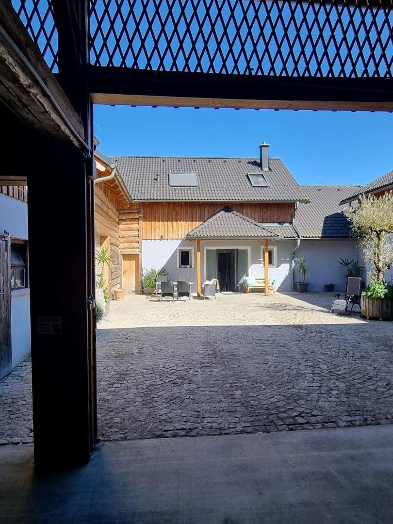 Blick in den gepflasterten Innenhof mit Sitzgelegenheiten und Zugang zum Wohnbereich.