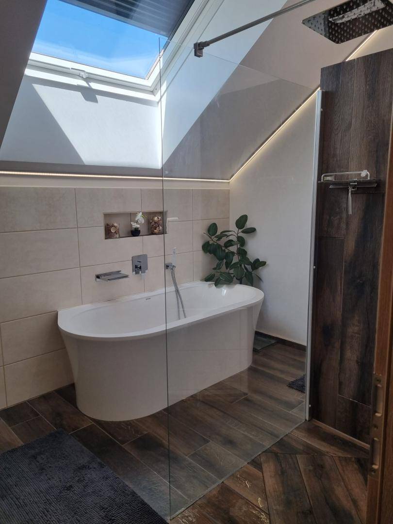 Modernes Badezimmer mit freistehender Badewanne, begehbarer Dusche und großem Dachfenster.