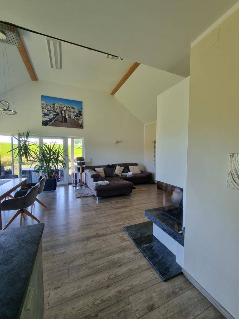 Gemütliches Wohnzimmer mit großem Sofa, modernem Kamin und hohen Decken mit Holzbalken.