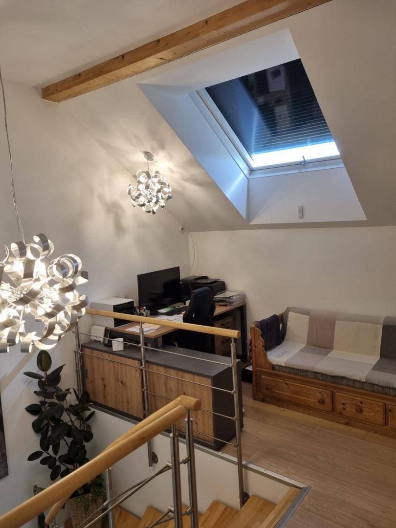 Helles Büro im Obergeschoss mit Blick auf die Treppe, Dachfenster und Holzbalken.