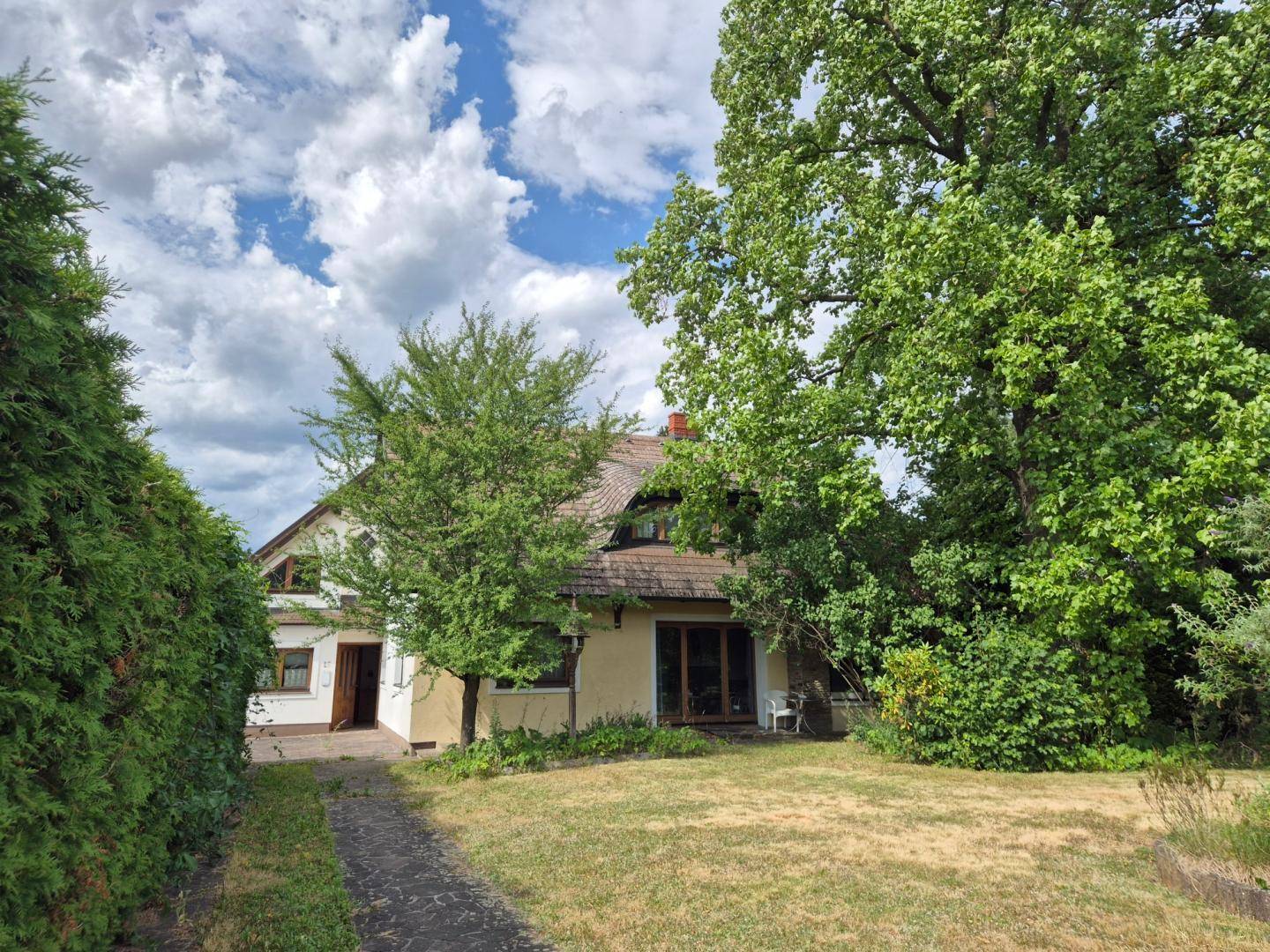 Idyllisches Einfamilienhaus umgeben von altem Baumbestand und einem weitläufigen Garten.