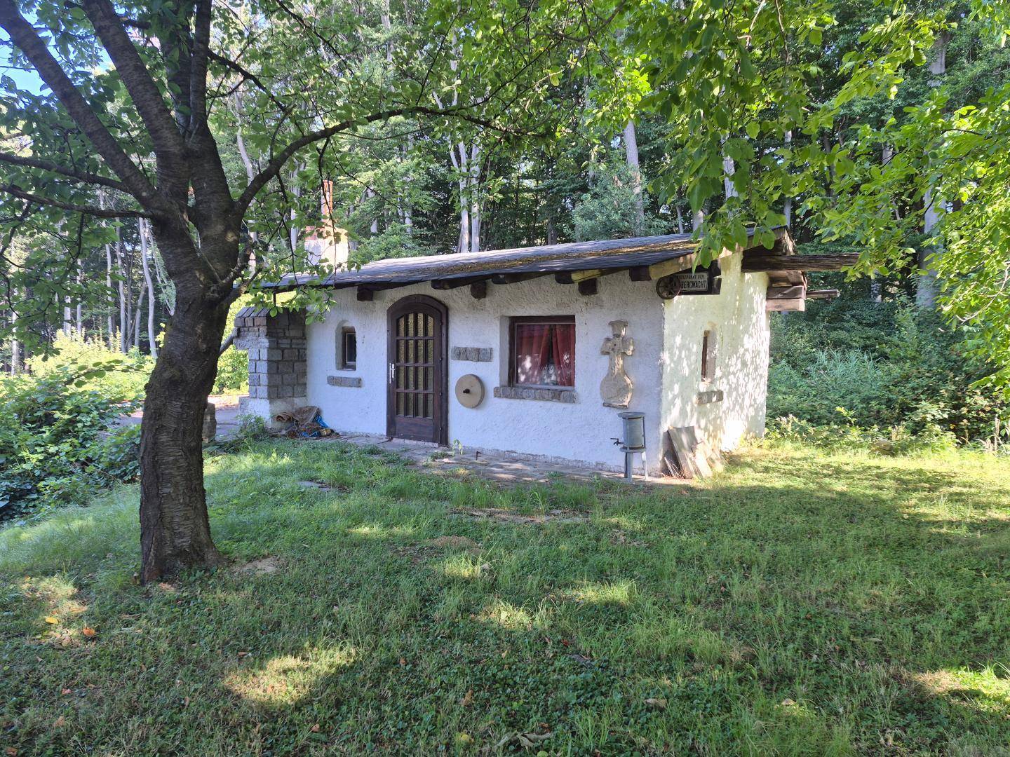 Charmantes kleines Nebengebäude oder Gartenhaus, umgeben von Rasen und Bäumen.