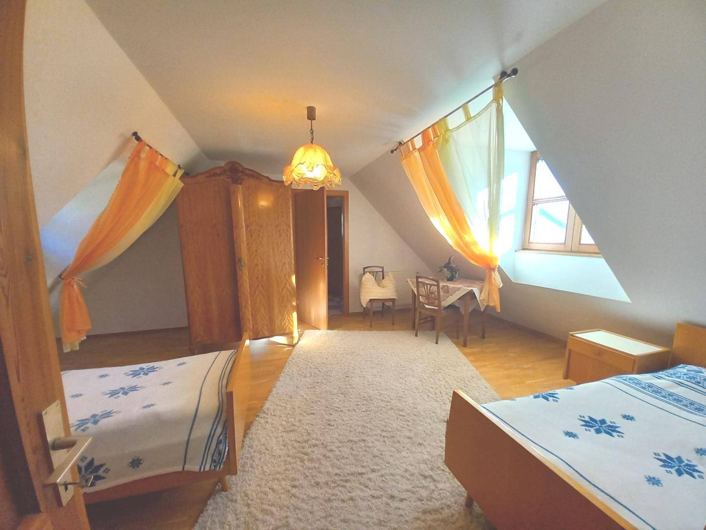 Schlafzimmer im Dachgeschoss mit schrägen Wänden, zwei Einzelbetten und einem Kleiderschrank.